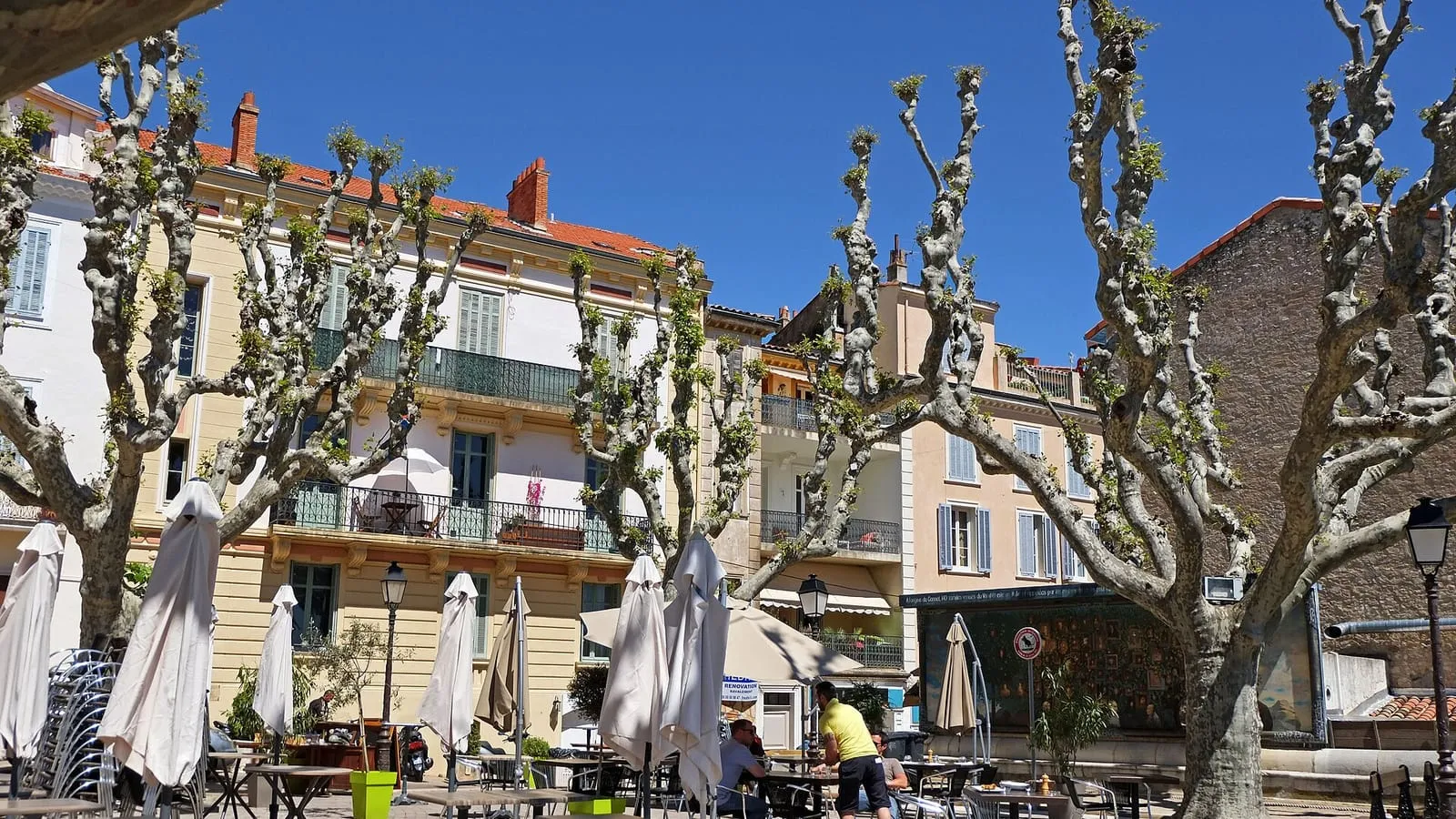La place Bellevue au Cannet, cœur de la vieille ville : platanes, terrasses de café et façades provençales colorées