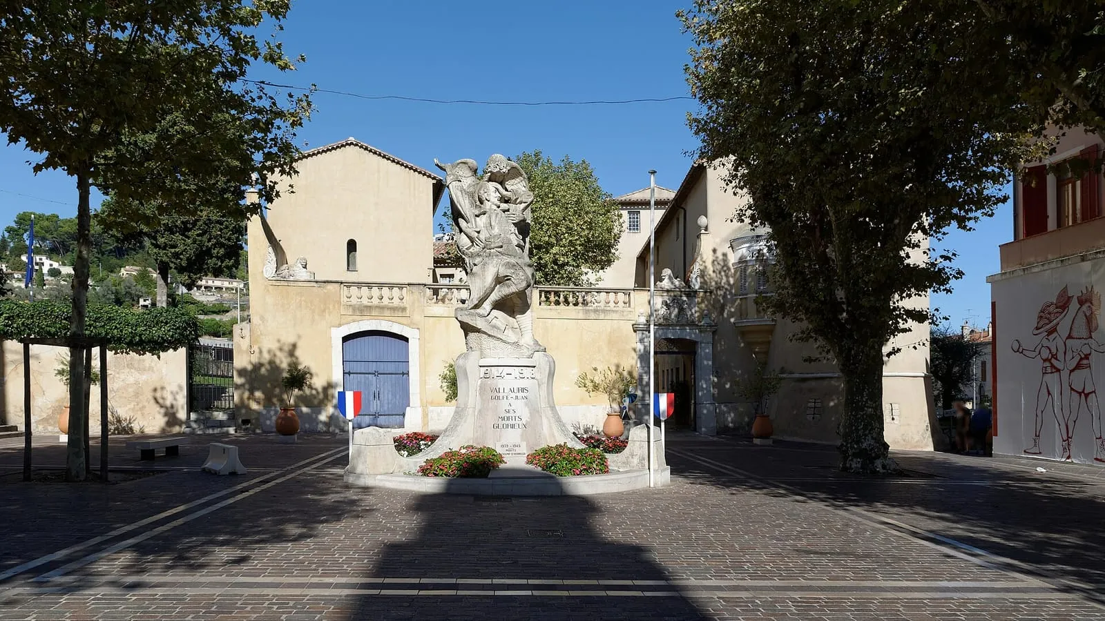 La place ensoleillée devant le château-musée de Vallauris, ses platanes et son monument fleuri au cœur de la ville des potiers